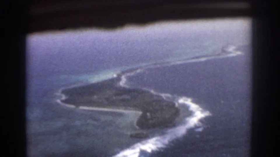 Aerial 8mm view near Perth, Australia, showing a small island or reef edged by white surf and blue-green shallows.