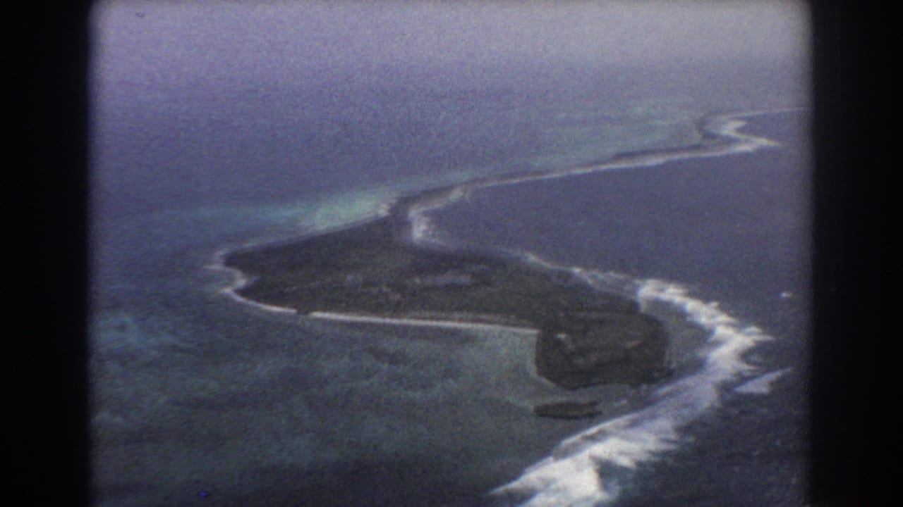Island coastline seen from above with reef breaks and open ocean beyond.