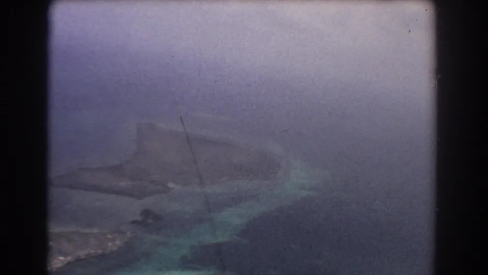 From the airplane window, the 1967 home movie shows a hazy reef and island coastline below near Perth, Australia.
