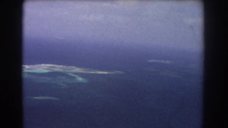 Late pan frame from 1967 8mm aerial footage near Perth, Australia, with distant reef, lagoon colors, and deep blue sea.