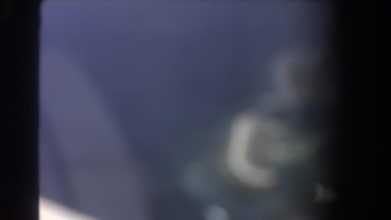 Blurred plane-window view with blue haze and a dark vertical frame edge.