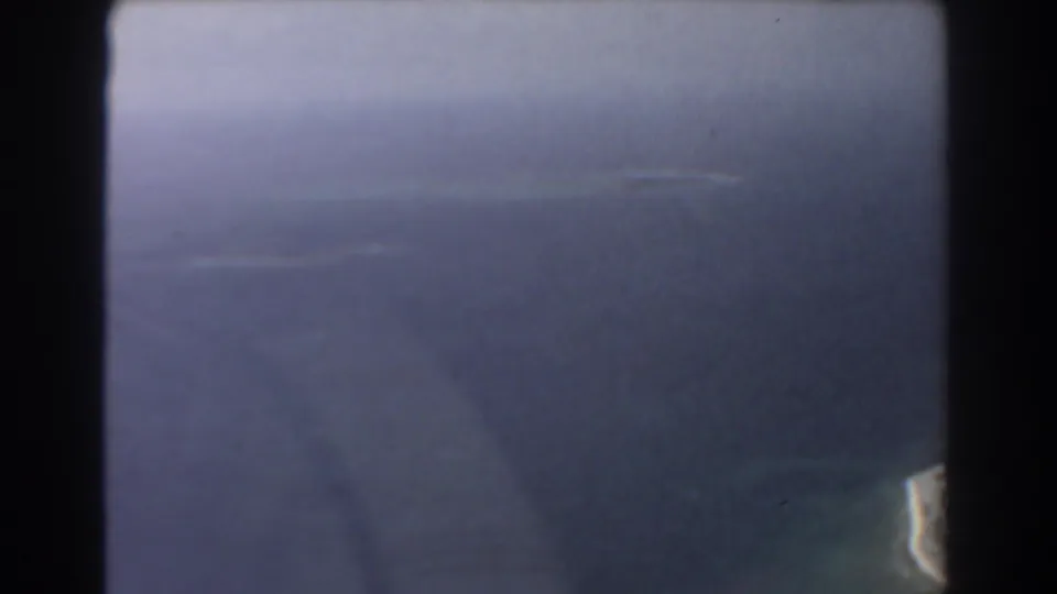 Late-frame 1967 Perth aerial view, showing indistinct land or water through a blue-tinted aircraft window.