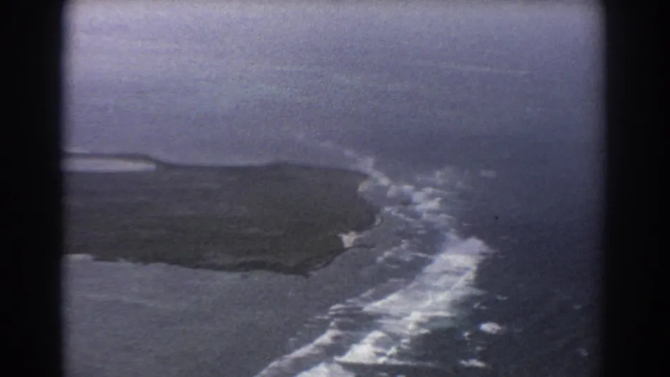 1967 8mm aerial view near Perth, Australia, showing an oblique pass over island shoreline, pale surf, and surrounding ocean.