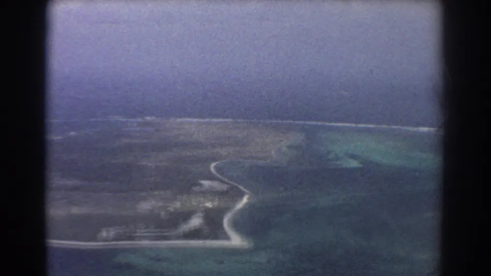 1967 Perth-area aerial frame with a pale shoreline, narrow landmass, turquoise shallows, and darker ocean beyond.