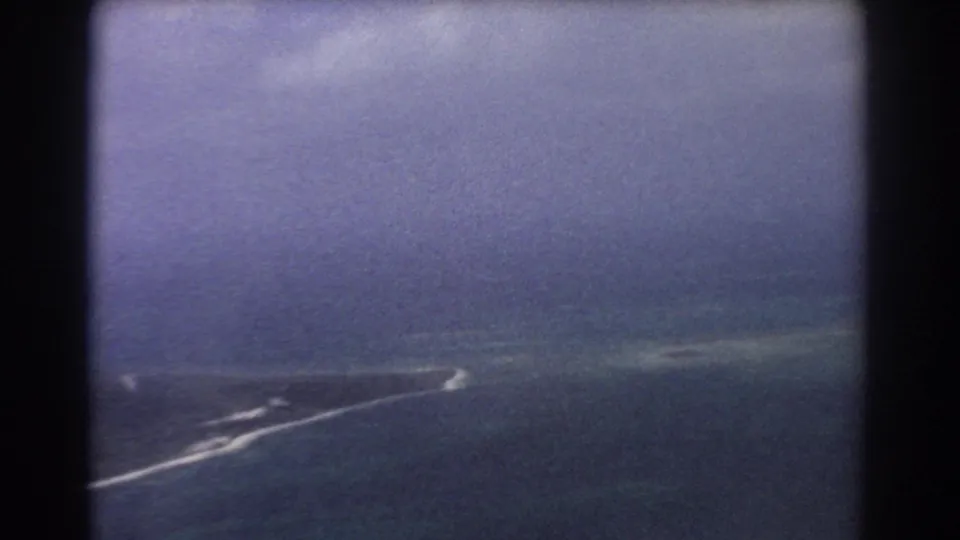 Aerial 8mm frame near Perth with blue ocean, pale coastal shallows, white surf, and dark vertical window framing.