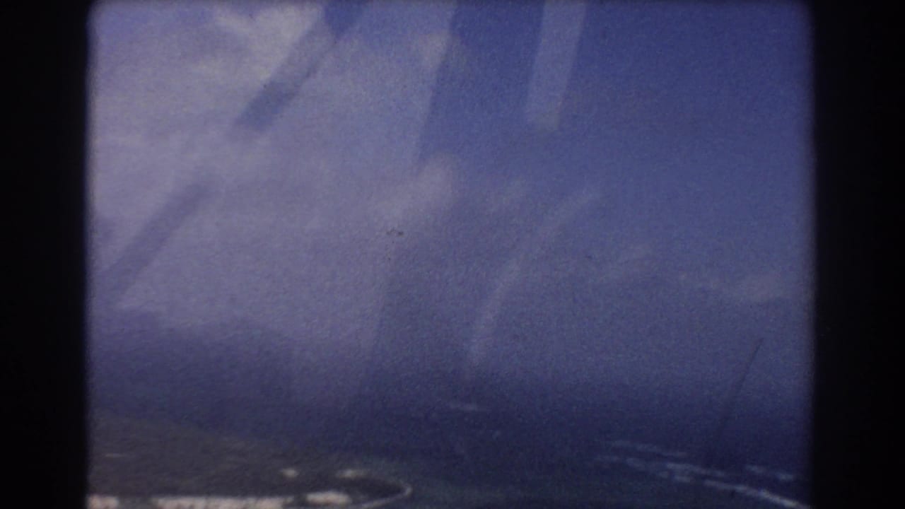 Soft blue aerial view through an aircraft window with coastline partly visible near the lower edge.
