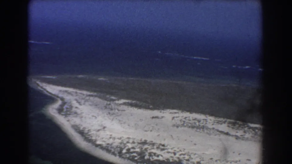 Vintage 8mm frame of a sandy coastal point and offshore surf lines from an aircraft perspective near Perth, Australia.