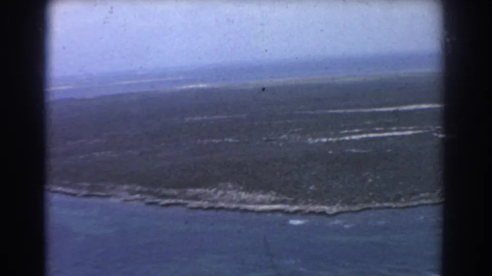 1967 8mm aerial view near Perth, Australia, showing flat coastal marshland, turquoise water, and a pale horizon.
