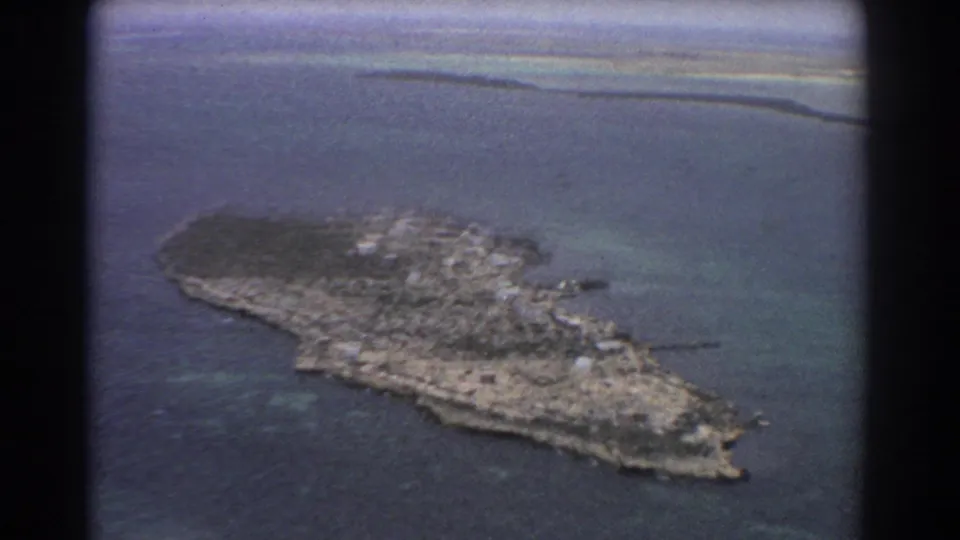 1967 Perth-area aerial frame with a compact island, pale coastal edge, reef shallows, and visible 8mm contact-sheet border.