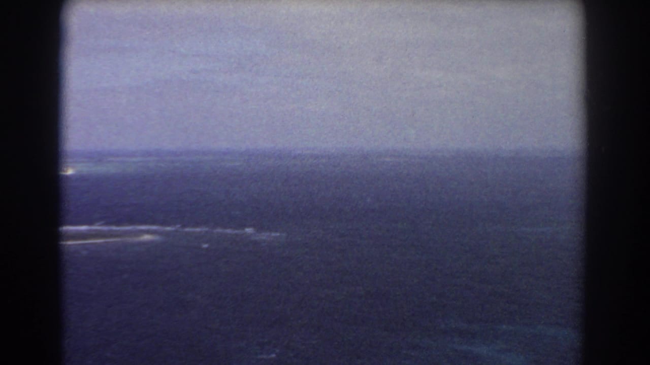 1967 8mm aerial footage near Perth showing open blue ocean, a distant horizon, and white reef or surf streaks.