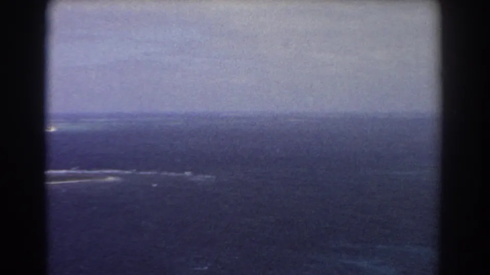 1967 8mm aerial footage near Perth showing open blue ocean, a distant horizon, and white reef or surf streaks.
