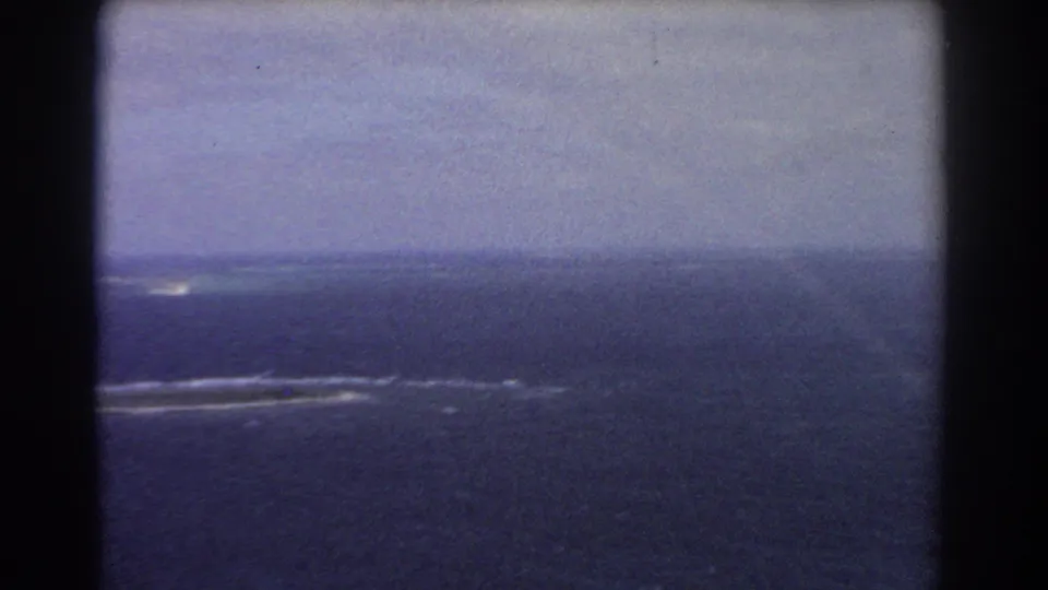 1967 Perth-area aerial 8mm frame showing blue ocean, low horizon, and white lines of surf or reef below.