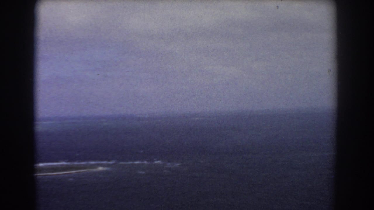 Distant ocean horizon with surf lines seen through dark 8mm frame borders.