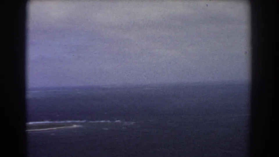 1967 8mm aerial view near the Perth, Australia collection context, showing open ocean and faint reef surf through a film-frame edge.