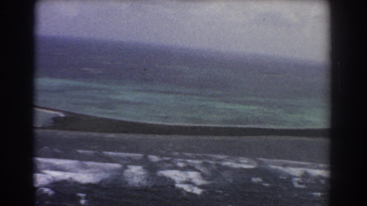 1967 Perth, Australia aerial 8mm frame showing turquoise shallows, darker ocean water, pale surf, and a hazy coastal horizon.