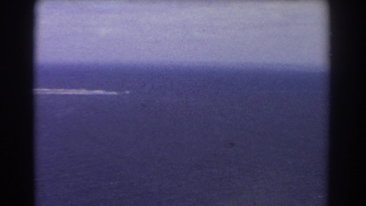 Open ocean with a thin white trail near the horizon.