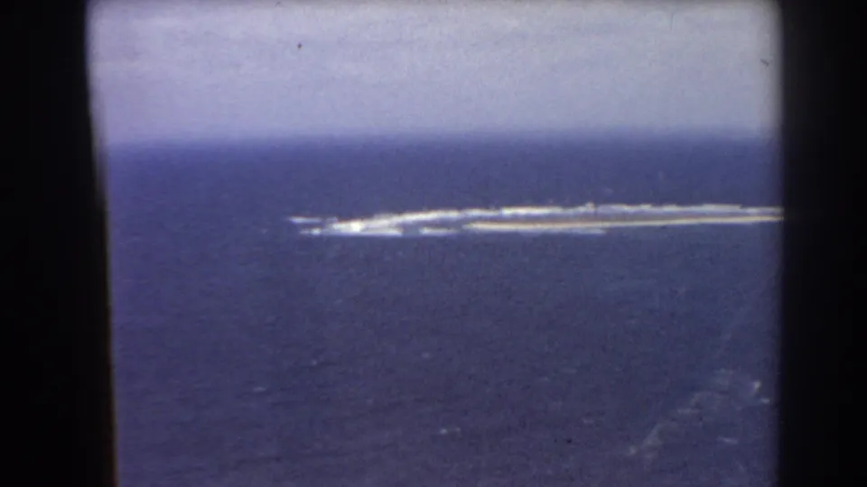 Perth-area 1967 home-movie frame with a longer bright wake cutting across the ocean surface.