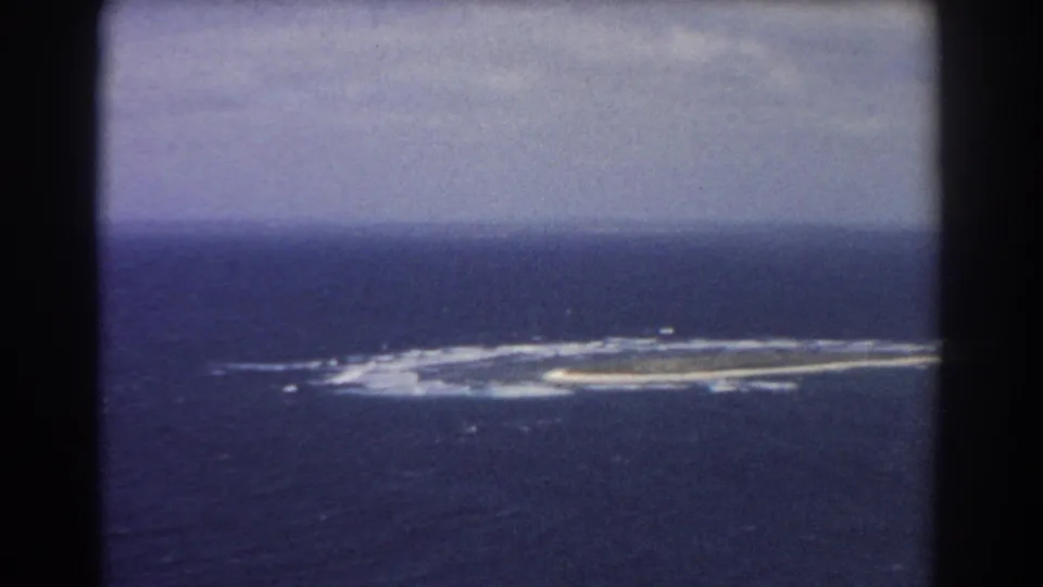 Perth-area 1967 home-movie frame with a closer view of the surf-edged feature in blue ocean under muted sky.
