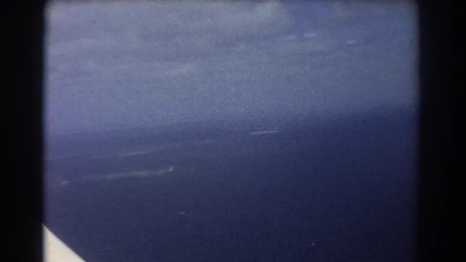 Final 1967 Perth-area aerial frame shifts from the island to hazy ocean and coastline seen through aircraft framing.