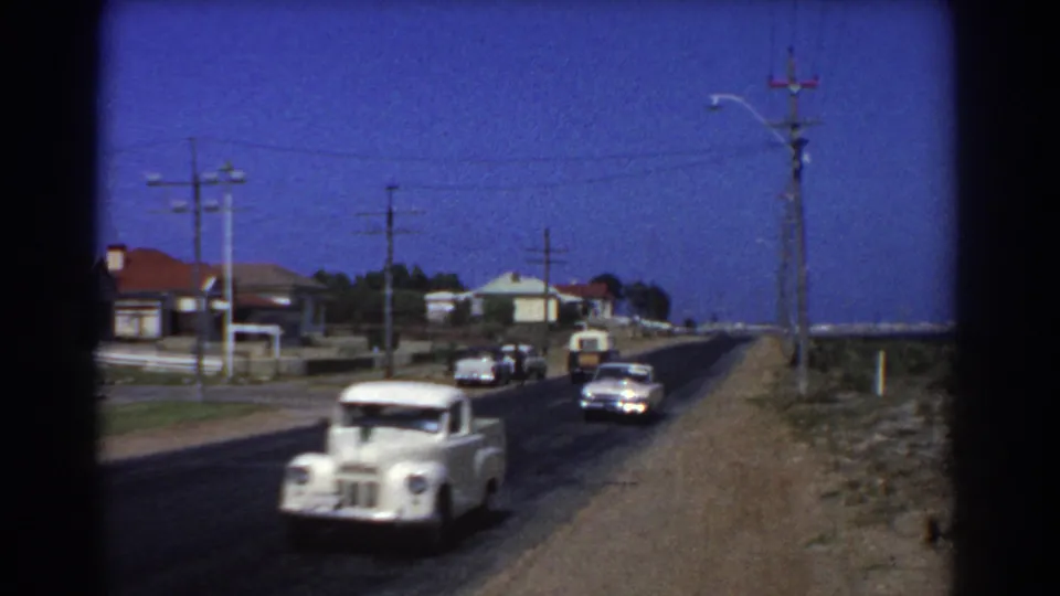 1967 Perth frame showing a white vintage truck on a suburban road, with houses, power poles, wires, and open verge visible.