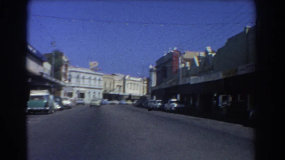 Perth town-center street in 1967 with parked cars, mid-century commercial facades, awnings, overhead wires, and a broad roadway.