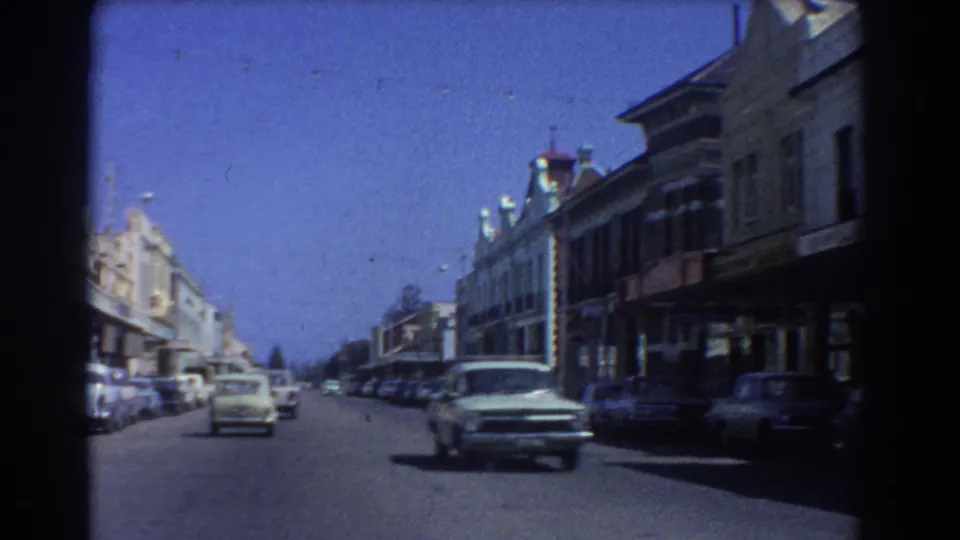 A 1967 Perth street scene shows cars moving through a commercial area lined with older buildings and parked vehicles.
