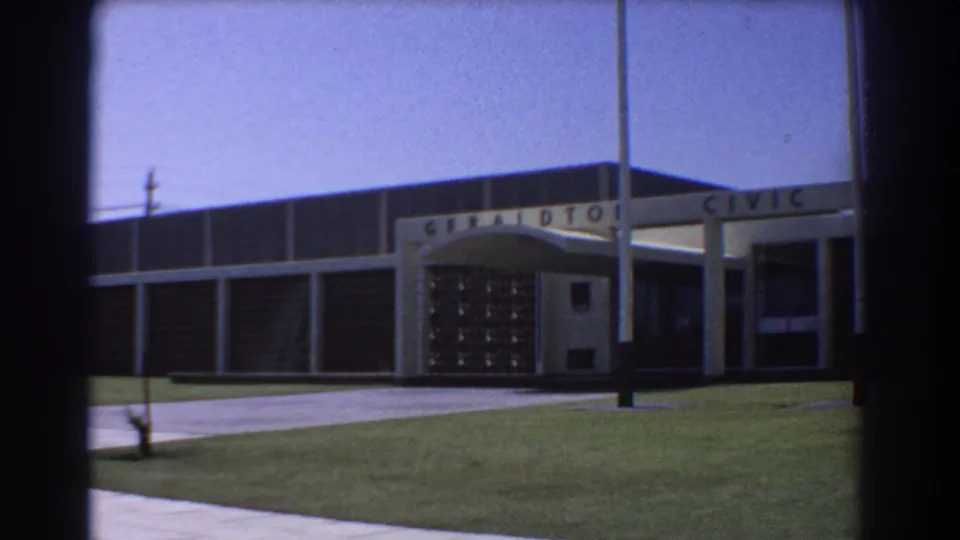 1967 8mm view of the Geraldton Civic Centre, centered on the entrance canopy, glass-block doorway area, walkway, and lawn.
