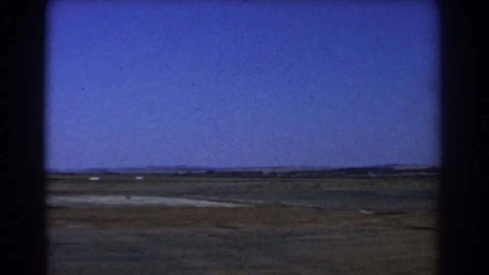 The final view shows a flat dry landscape near Perth with a distant horizon, bright blue sky, and dark 8mm film borders.
