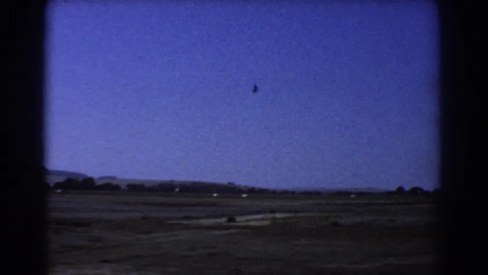 Perth, Australia landscape view from 1967 footage, with open field, low distant landforms, sparse trees, and visible 8mm frame borders.