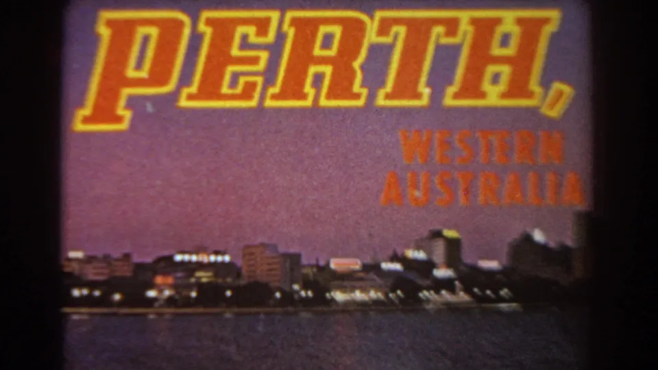 Second 1967 8mm frame of the Perth, Western Australia title card with skyline lights and water below.