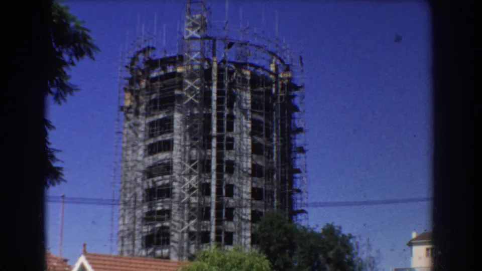 Perth 1967 8mm frame showing the scaffolded circular building closer in view, with rooftops and trees below.