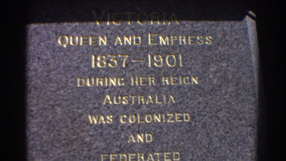 Close handheld 8mm view of the Queen Victoria plaque in Perth, with the inscription centered and dark film border at the side.