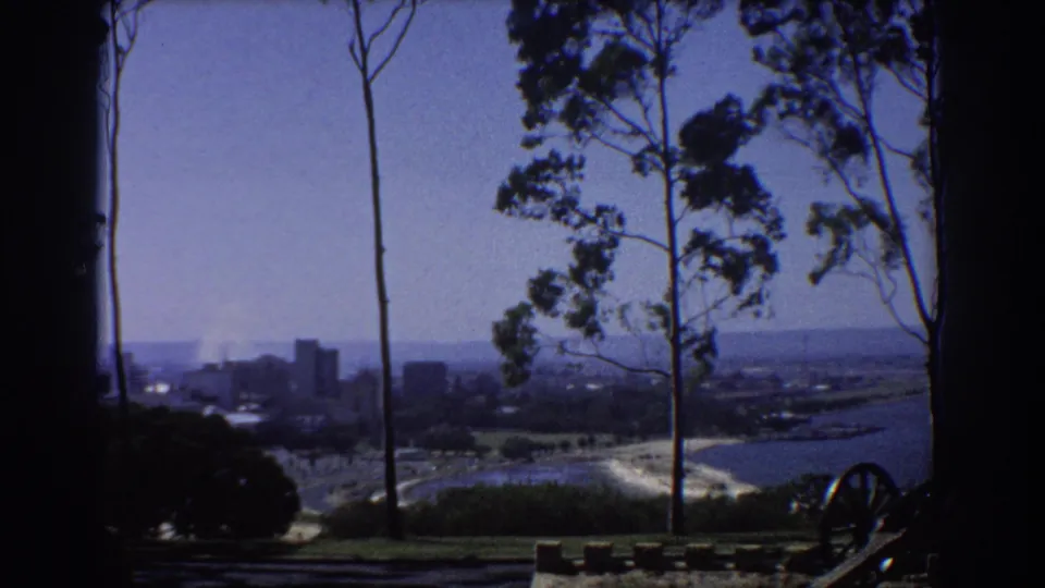 Final 1967 Perth view from the lookout, with eucalyptus trunks, distant skyline, river edge, and cannon wheel detail at lower right.