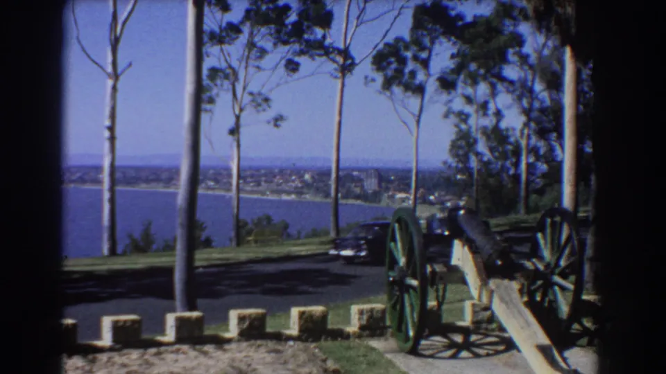 1960s Perth overlook view with a black car at the cannon display and a broad blue waterway in the background.