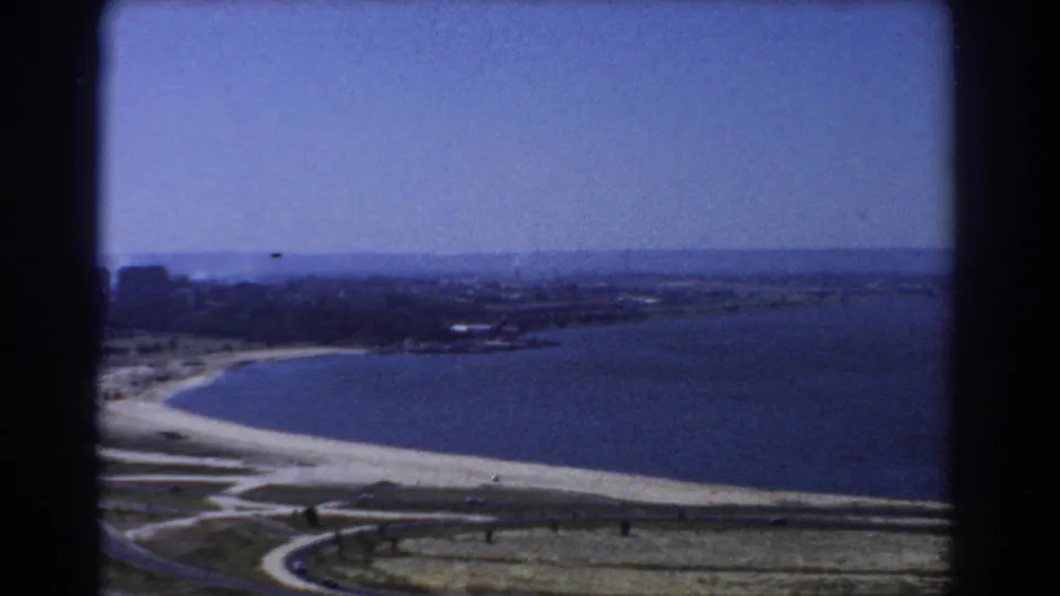 1967 Perth coastal panorama showing a pale beach, blue bay water, low shoreline development and distant horizon.