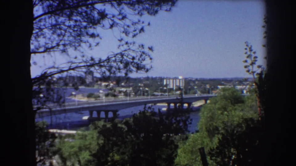 Perth, Australia city view from 1967 8mm footage, with a broad bridge crossing water beneath a clear sky.