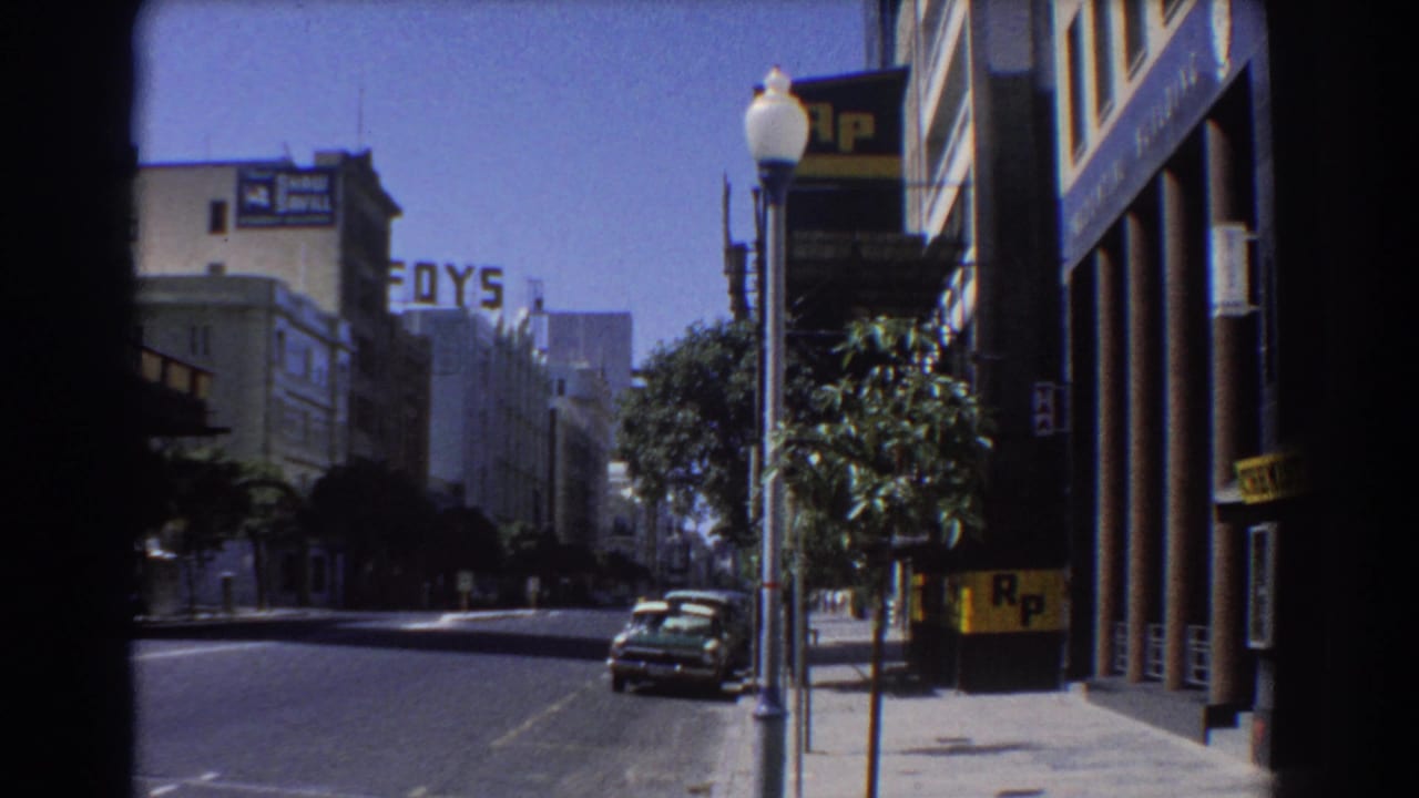 Sunny Perth street with parked car, lamppost, FOYS sign, and R.P. building signage.