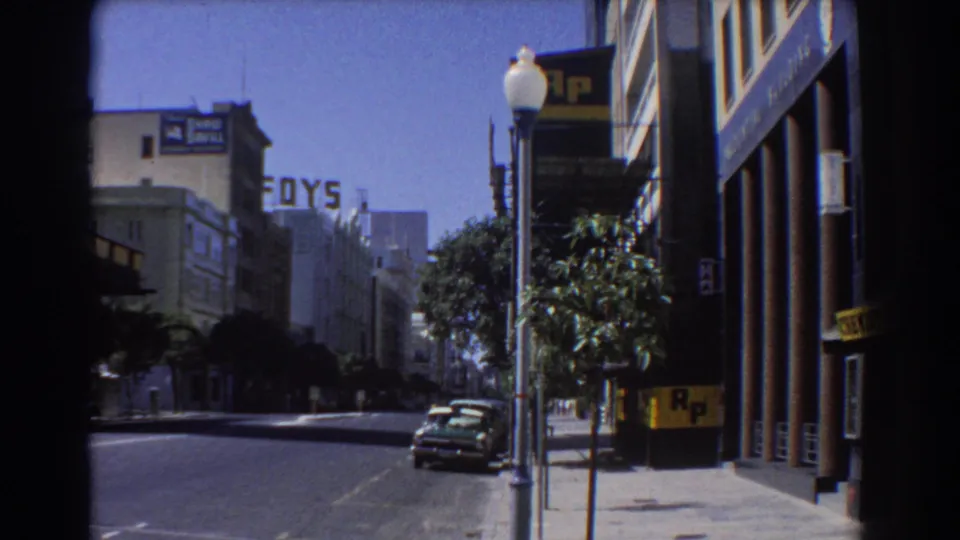1967 Perth street view showing parked cars, a lamppost, trees, FOYS lettering, and R.P. signage on commercial buildings.