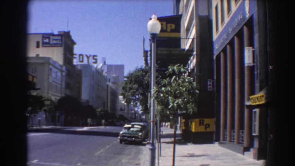1967 Perth commercial street with a parked car, lamppost, trees, FOYS lettering, and R.P. signage visible along the sidewalk.