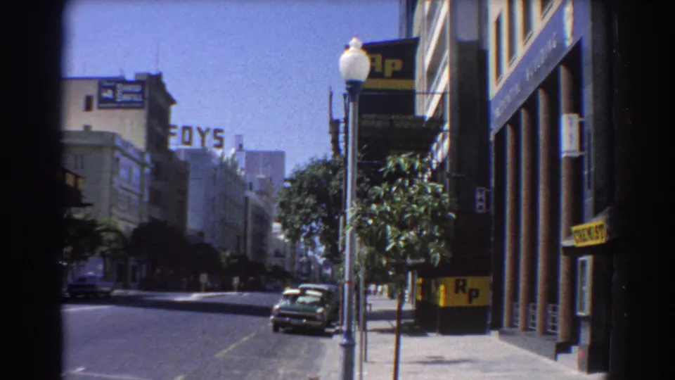 1967 Perth street view with mid-century cars, a lamppost, sidewalk trees, FOYS lettering, and R.P. signs on nearby buildings.