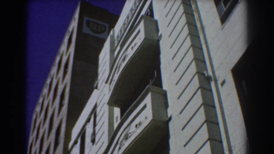 1967 Perth low-angle view of commercial building facades with balcony rails, windows, a BP sign and strong contrast from the 8mm exposure.
