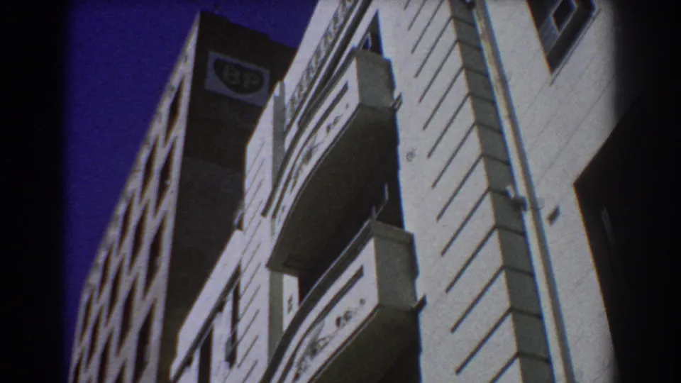 1967 Perth frame with a steep upward view of sunlit building facades, projecting balconies, and a BP sign at the upper left.