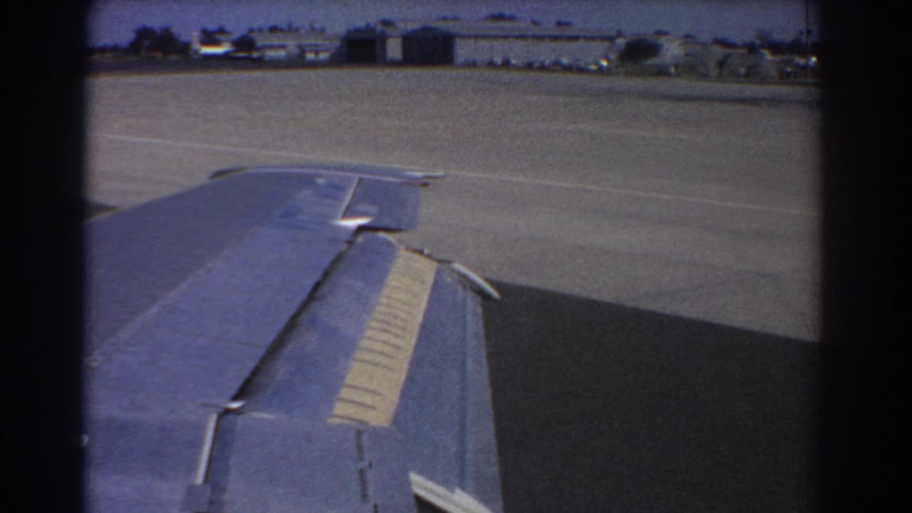 Aircraft wing seen through a window as the plane moves on airport tarmac.