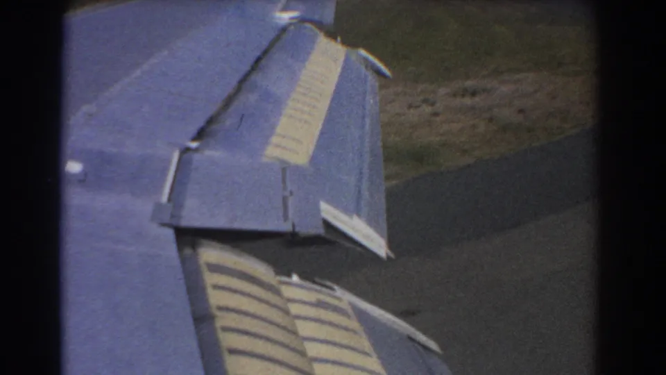 Blue plane wing with striped flaps viewed from inside the aircraft during a 1967 descent near Perth.