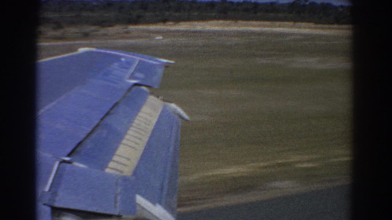 Aircraft wing over grassy airfield during takeoff roll.