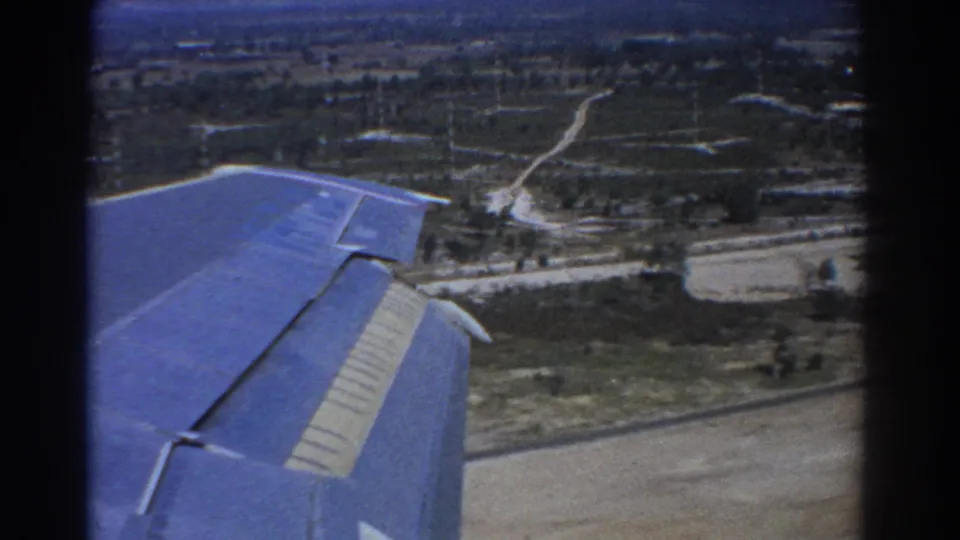 1967 Perth-area 8mm frame with the blue aircraft wing over roads, fields and scattered low buildings just before landing.