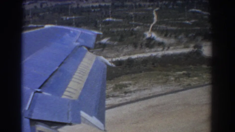 1967 8mm view near Perth showing a blue airplane wing over farmland, roads, and scattered rural terrain.