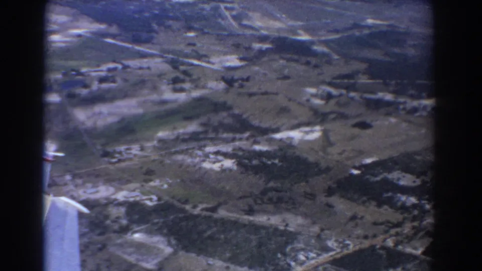 Aerial home-movie view over open land near Perth, with the wing edge at left and roads visible below.