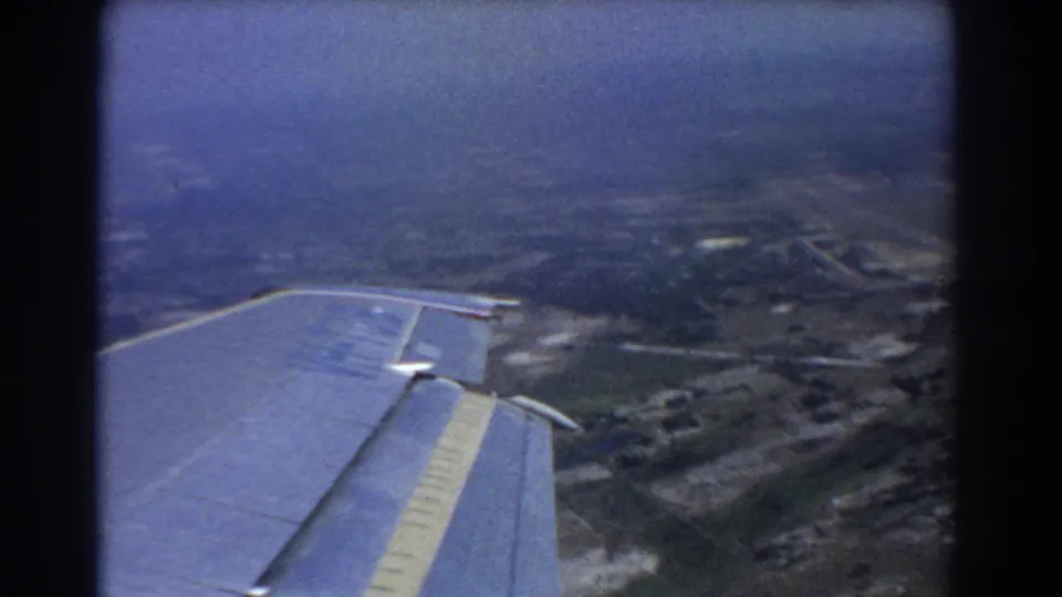 Aerial passenger view near Perth in 1967, with a plane wing crossing hazy fields, roads, and low-density development.