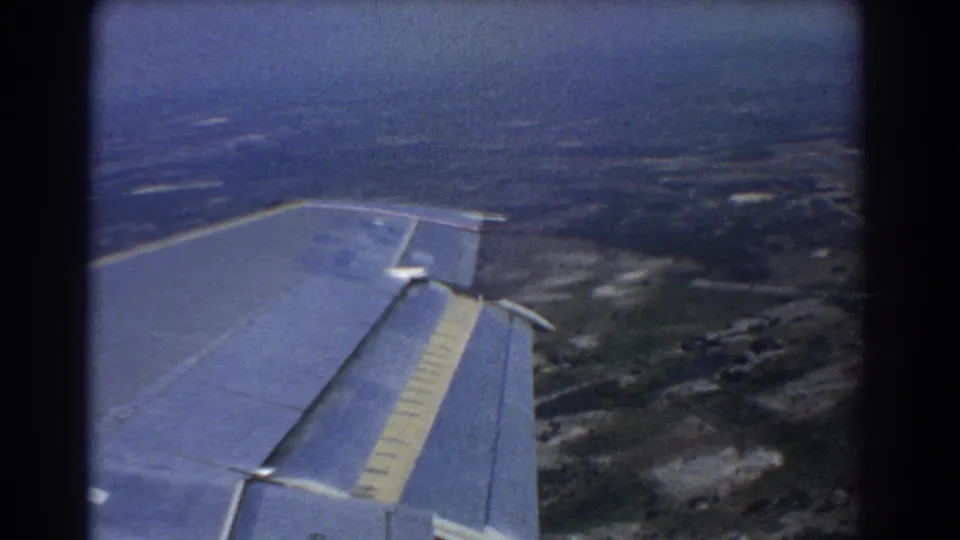 Passenger-window view from a 1967 flight near Perth, showing the airplane wing above fields, roads, and hazy terrain.